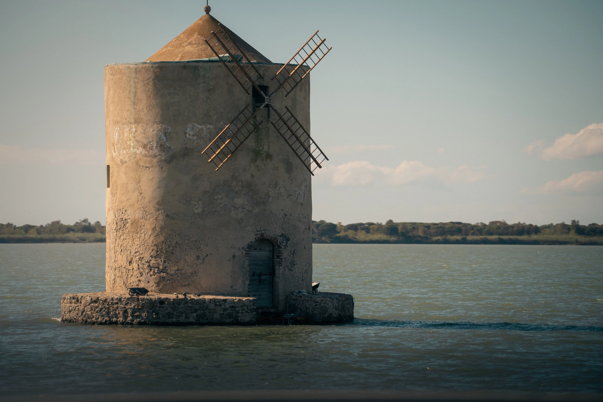 A weathered stone windmill standing at the water’s edge