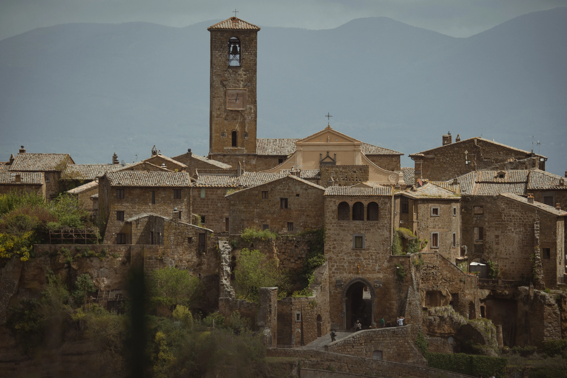 A stone town and clocktower against distant mountain slopes
